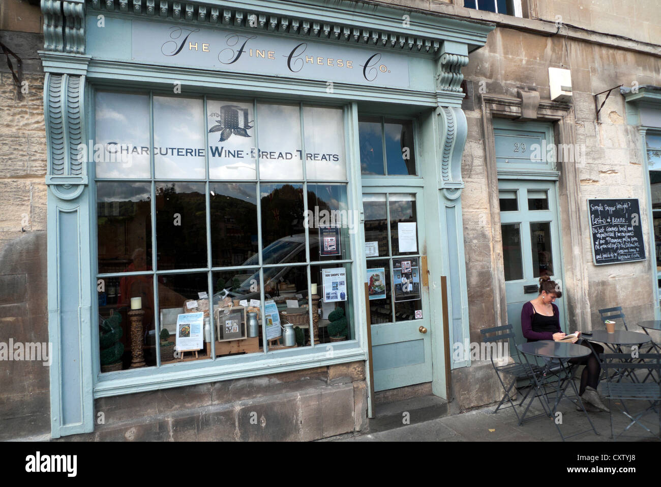 Une femme assise à l'extérieur de la société Fromages fins sur Walcot Street dans la ville de Bath, Avon, Somerset, Angleterre KATHY DEWITT Banque D'Images