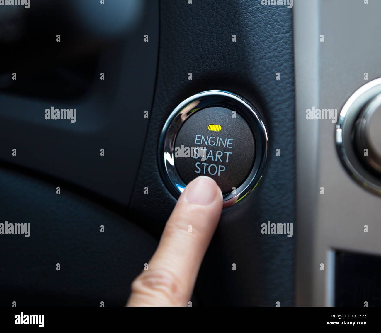 Doigt qui appuie sur le bouton d'arrêt de démarrage du moteur d'une voiture Banque D'Images