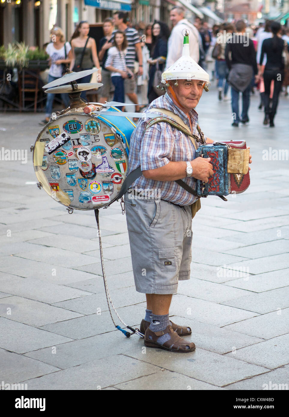 Un one man band jouant un accordéon concertina ou petite,cymbales, grosse caisse et d'un entonnoir avec des cloches sur sa tête. Banque D'Images