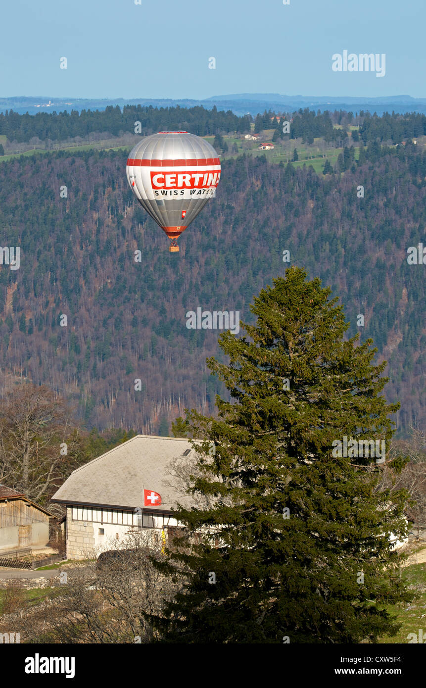 Hot Air Balloon volant à basse altitude au-dessus d'une ferme dans les montagnes du Jura, Suisse Banque D'Images