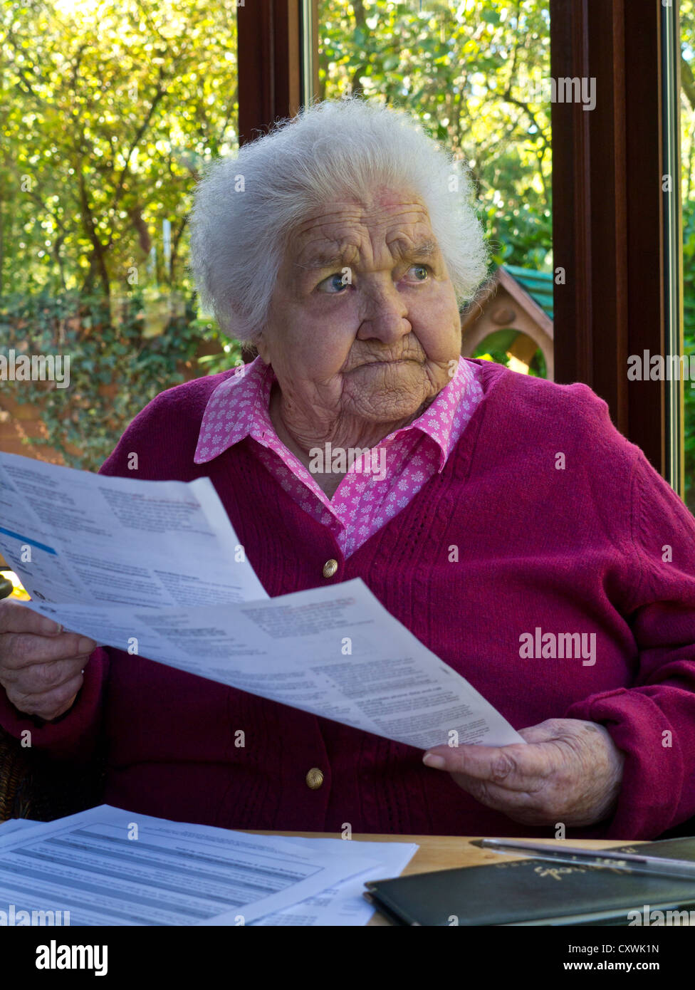 FACTURES DE CARBURANT D'ÉNERGIE DÉCLARATIONS LES PERSONNES ÂGÉES INQUIÈTENT une vieille dame âgée à la maison lisant et contemplant ses derniers États financiers et factures Banque D'Images