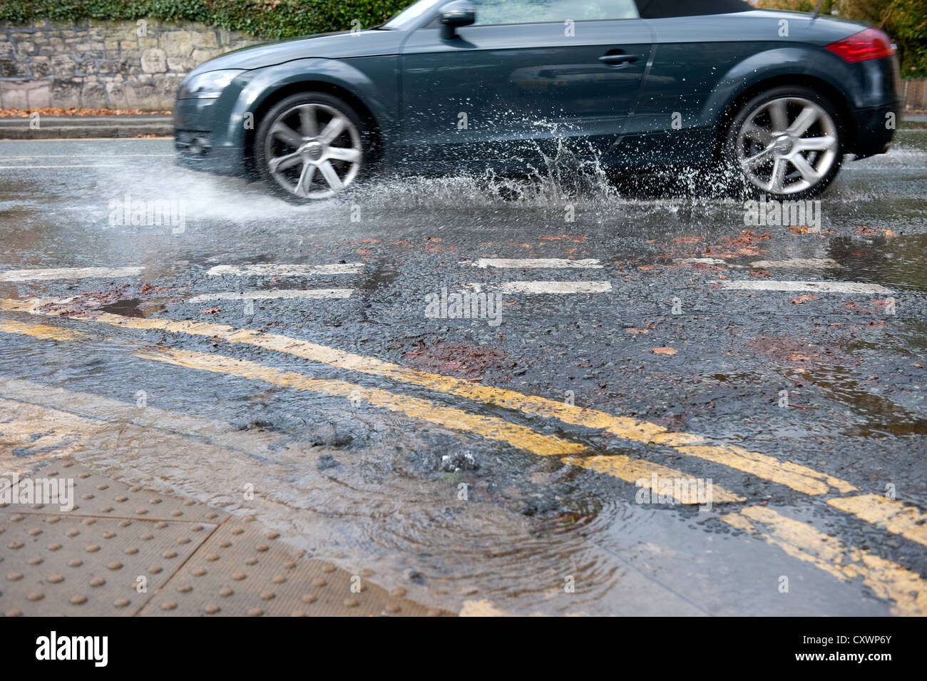 L'eau des inondations en rafale de la canalisation principale route avec des voitures passant devant Banque D'Images