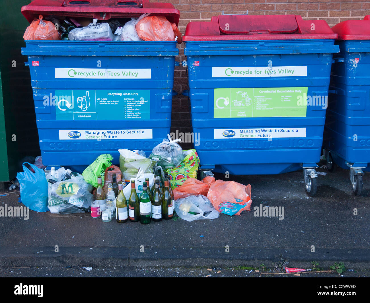 Bac de recyclage pour le verre mélangé trop remplis et avec des bouteilles entassées à côté Banque D'Images