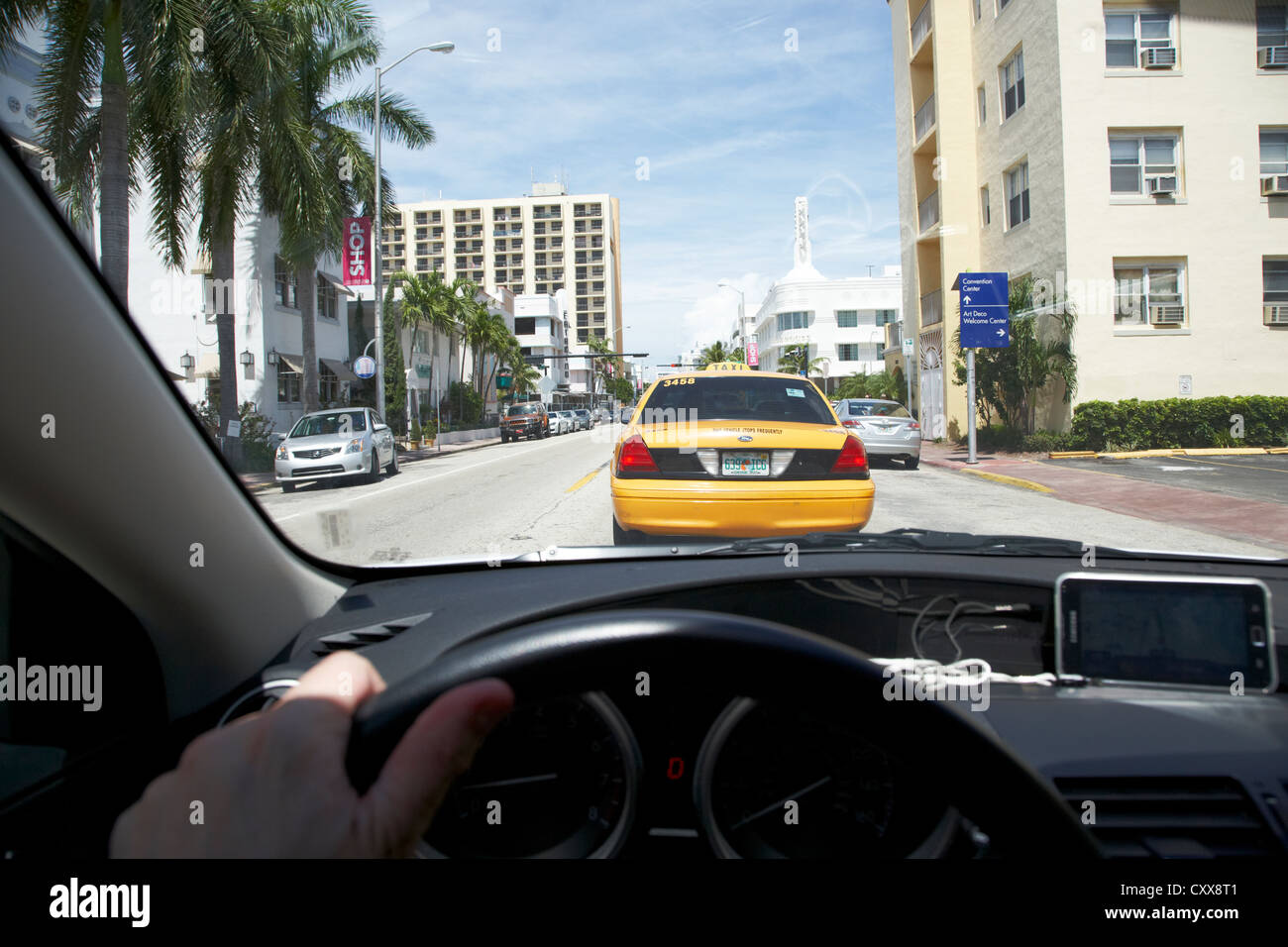 Mans part sur la roue en voiture sur Collins Avenue à Miami South Beach à la suite d'un yellow cab, florida usa Banque D'Images