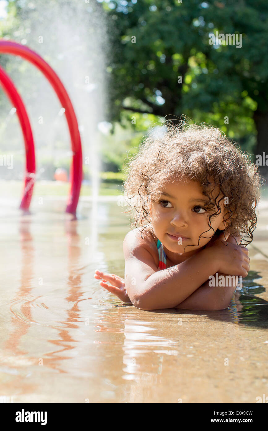 Mixed Race girl playing in fountain Banque D'Images