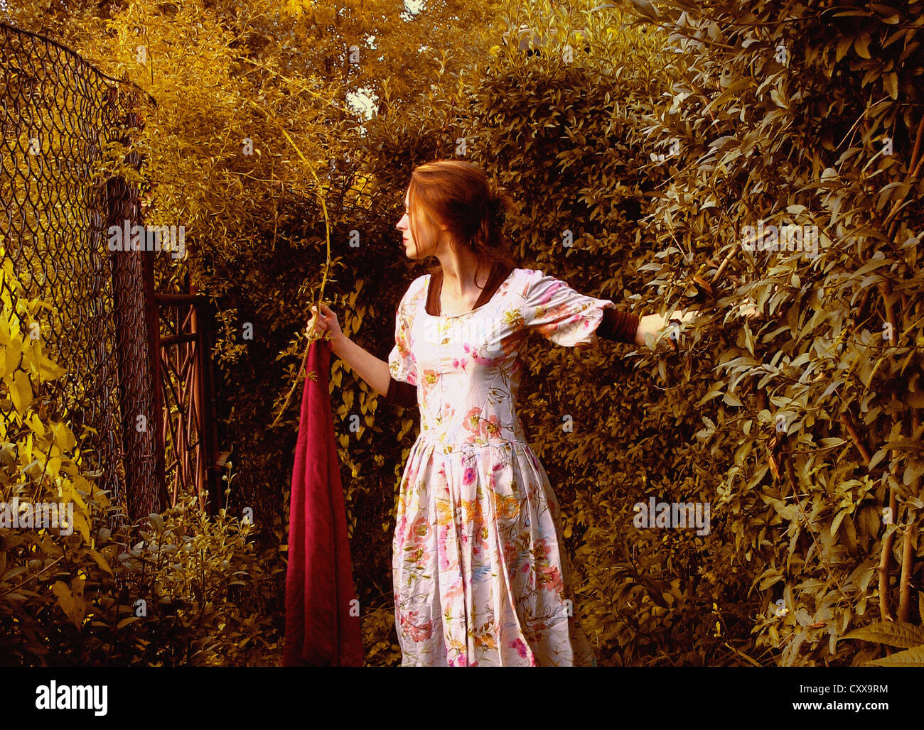 Une femme en robe blanche, debout dans un jardin et la tenue d'une longue écharpe  rouge Photo Stock - Alamy