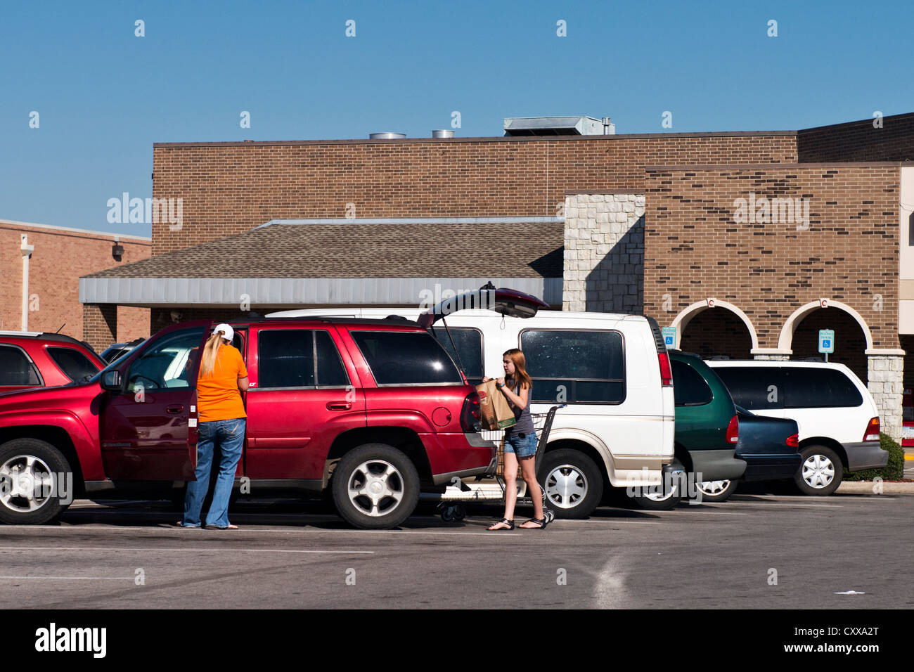 Une mère et fille entre mettre de la nourriture dans leurs sacs automobile dans le stationnement d'un supermarché. Oklahoma City, Oklahoma, USA. Banque D'Images