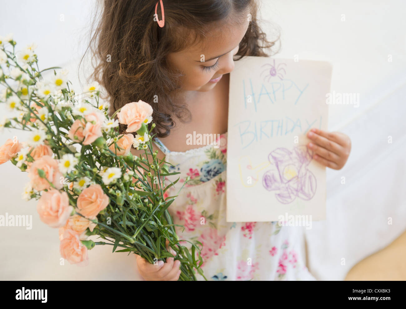 Mixed Race girl holding Flowers et carte d'anniversaire Banque D'Images