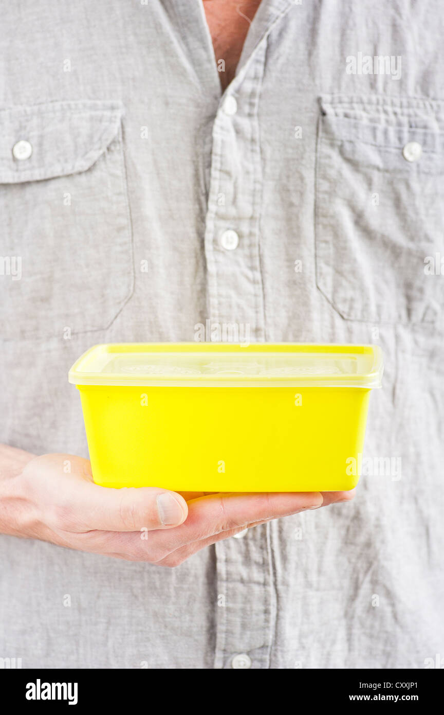 Face de l'homme avec une boîte en plastique jaune dans sa main Banque D'Images