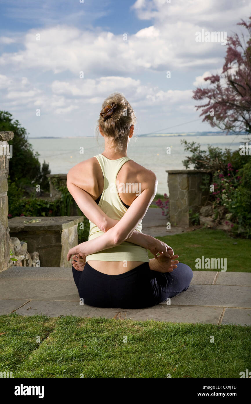 Professeur de yoga en position sur l'étape en jardin avec vue sur mer Banque D'Images