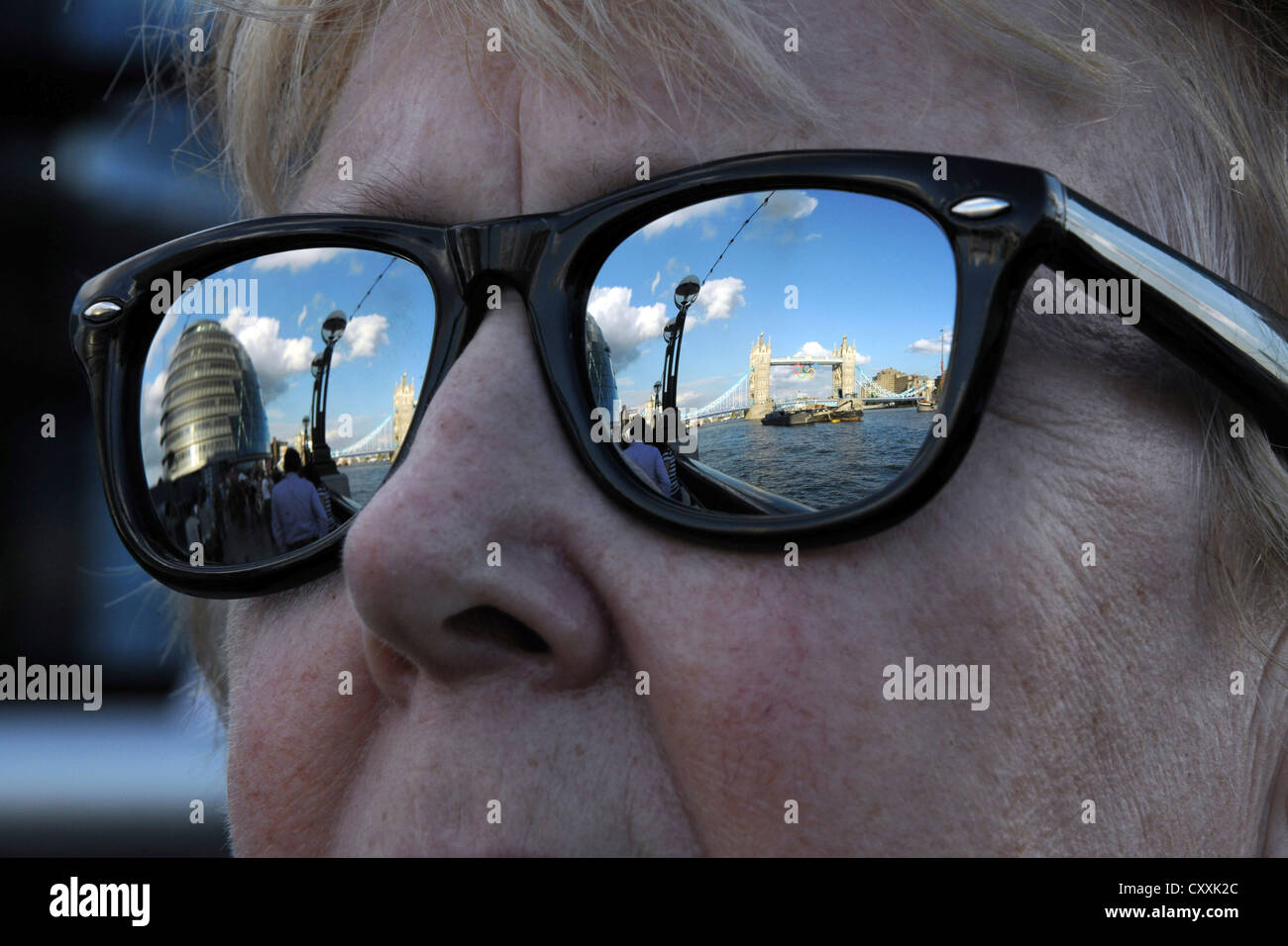 Le Tower Bridge et la Tamise reflète dans a woman's lunettes de soleil. Banque D'Images