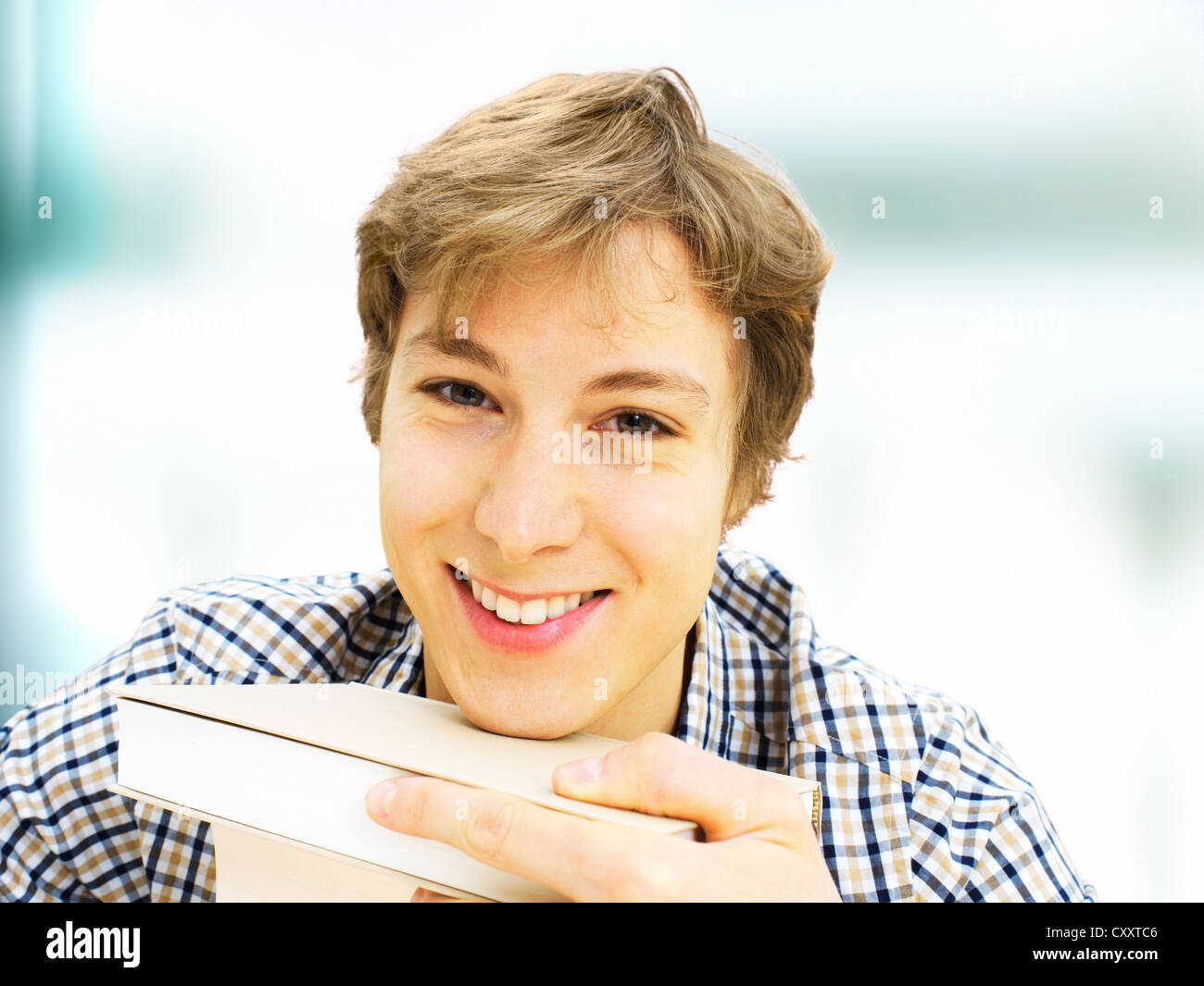 Smiling student avec une pile de livres Banque D'Images