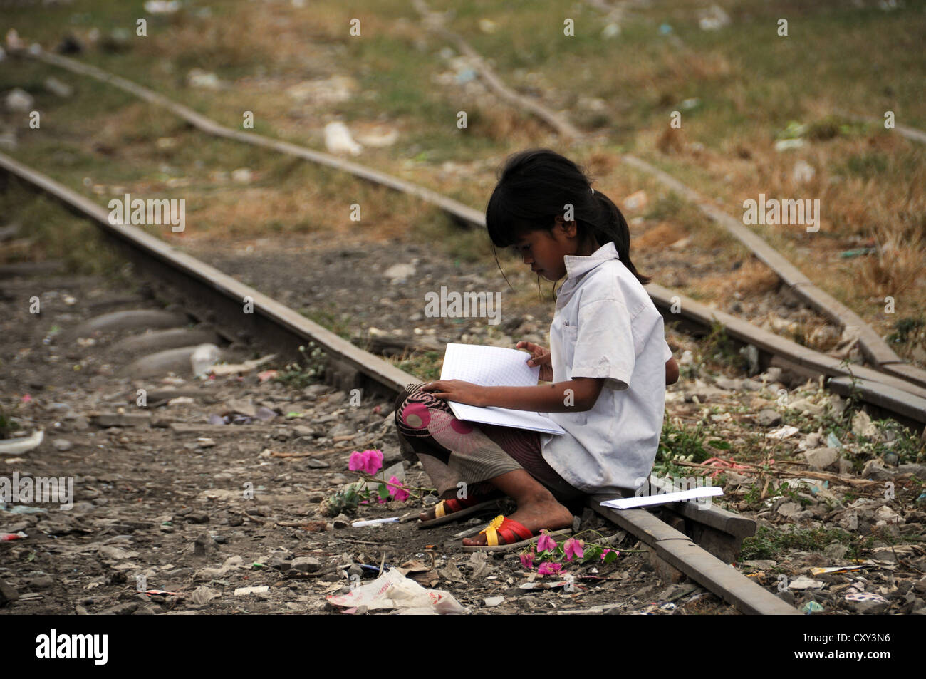 Fille cambodgienne l'apprentissage avec un livre, assis sur une ancienne voie de chemin de fer, Battambang, Cambodge, Asie Banque D'Images