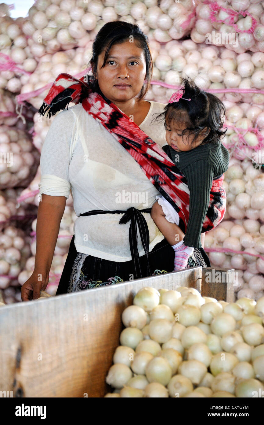Indigene femme portant une petite fille dans une écharpe, debout devant des sacs d'oignons, CENMA, légumes du marché de gros la Banque D'Images