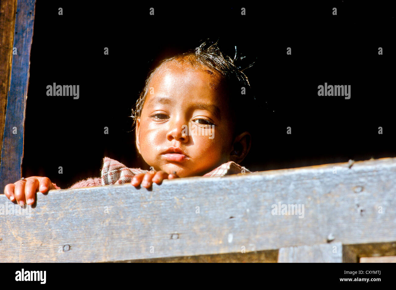 Petit garçon curieusement à la recherche d'une fenêtre dans le petit village de Gangi, l'Inde, l'Asie Banque D'Images