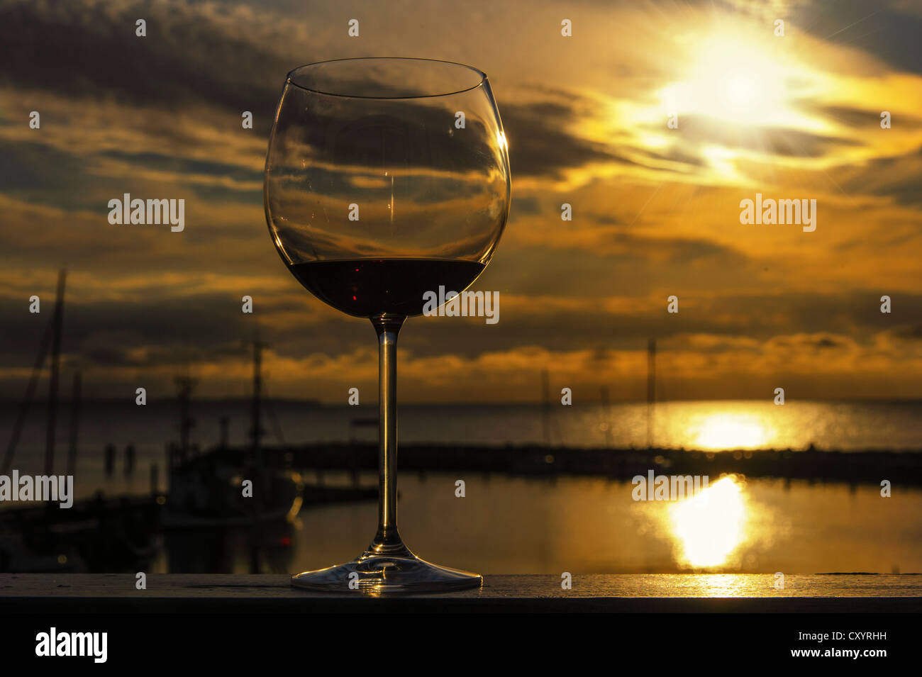 Verre de vin rouge sur la rampe d'un balcon au coucher du soleil, donnant sur le port, Timmendorf, Mecklembourg-Poméranie-Occidentale Banque D'Images