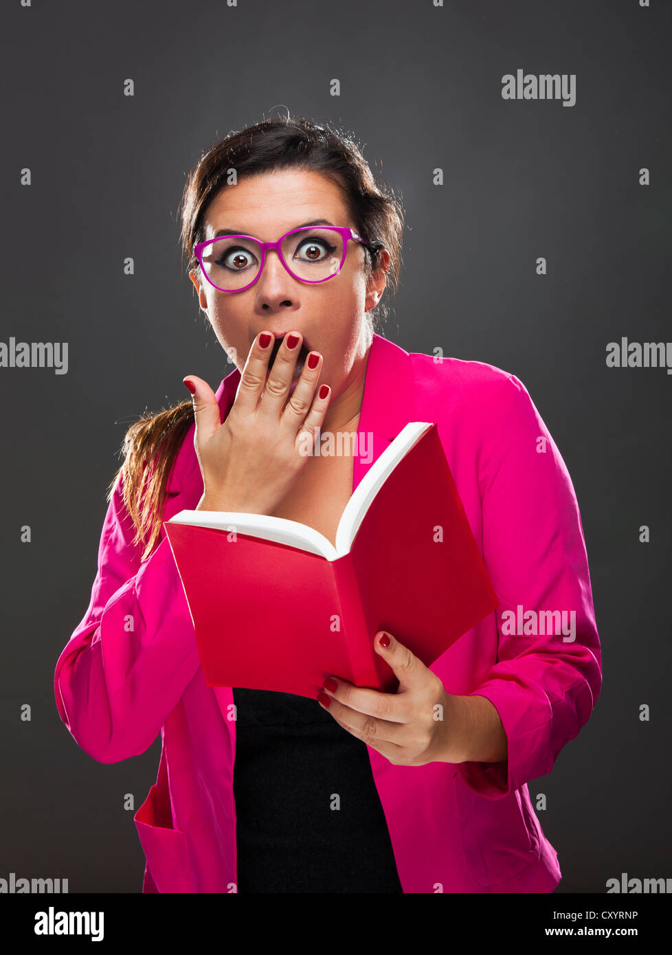 Femme d'âge moyen avec une expression étonnée et tenant un livre rouge Banque D'Images