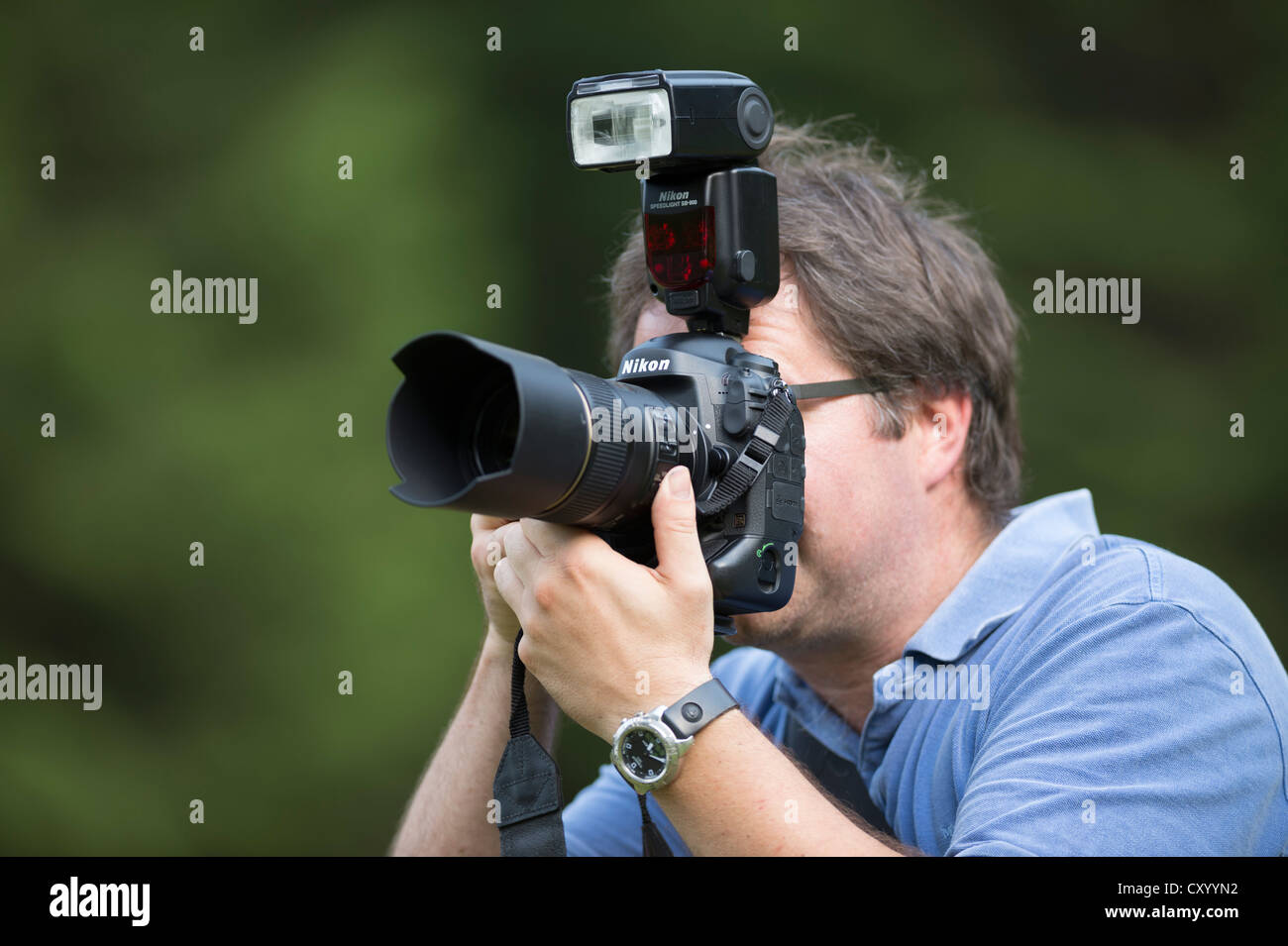 Photographe, entre 40 et 46, prendre des photos, à travers le viseur d'un Nikon D4 appareil photo numérique reflex avec une chaussure-monté Banque D'Images
