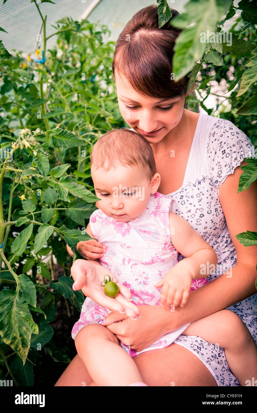 Mère et sa petite fille avec tomates non mûres Banque D'Images