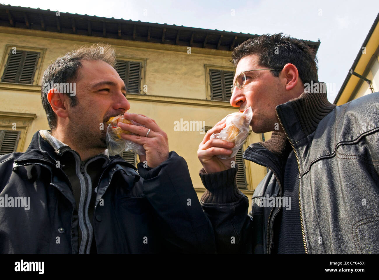 Deux hommes mangeant lampredotto tripes à la Florentine (sandwich sandwich) Piazza dei Nerli, Firenze (Florence), Toscane, Italie, Europe Banque D'Images