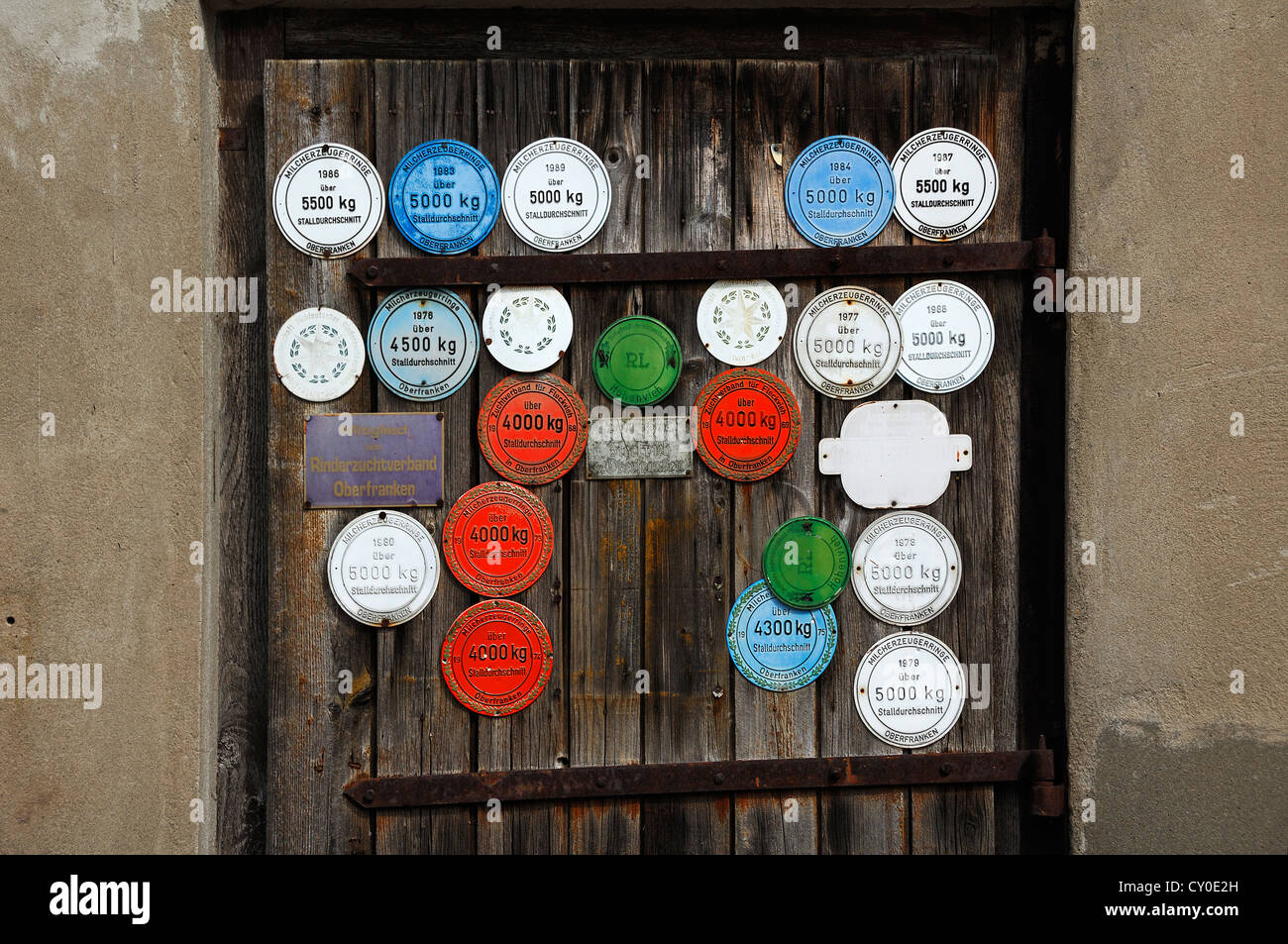 Plaques sur une porte de grange pour l'assemblée annuelle la production de lait de vaches, Wildenfels, Haute-Franconie Banque D'Images