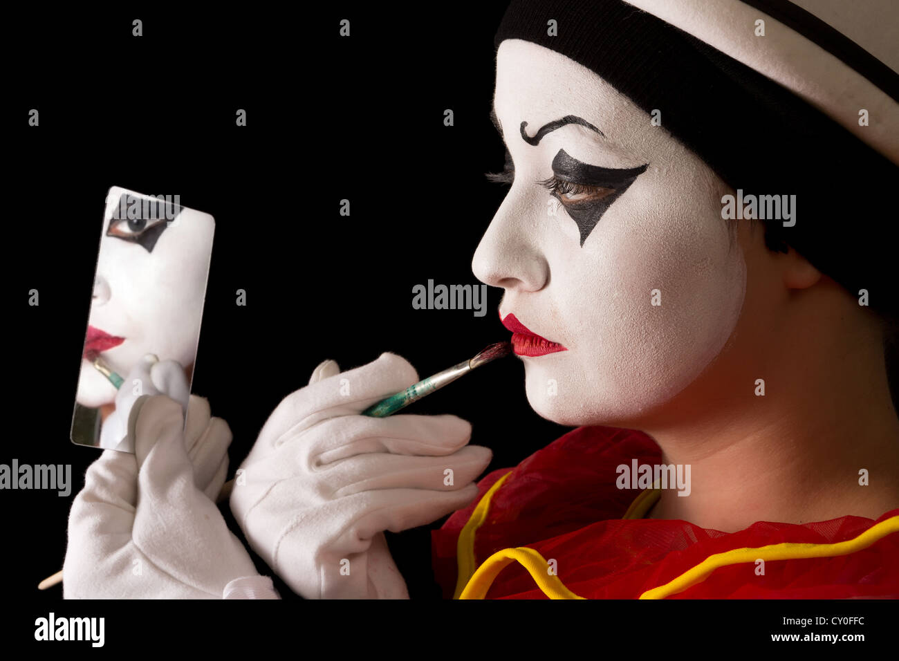 Artiste Mime Pierrot appliquant la peinture pour le visage avec un pinceau Banque D'Images