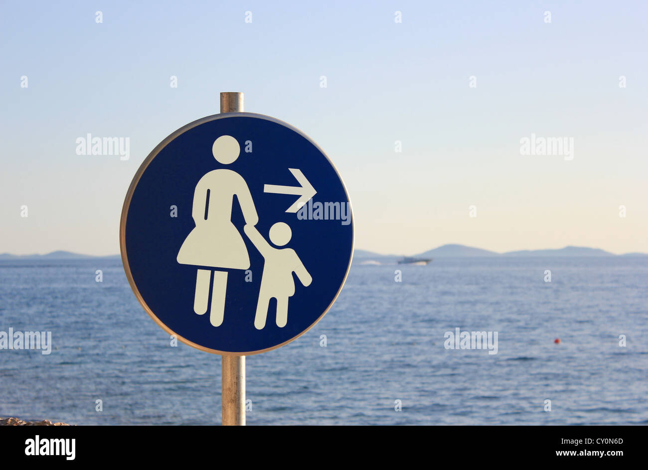 La mère et l'enfant direction - signe de la circulation chemin de plage avec la mer en arrière-plan Banque D'Images