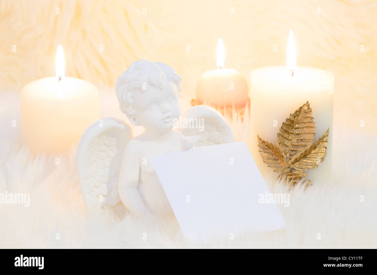 Un ange entouré par des bougies tenant une feuille blanche pour la liste de souhaits Banque D'Images