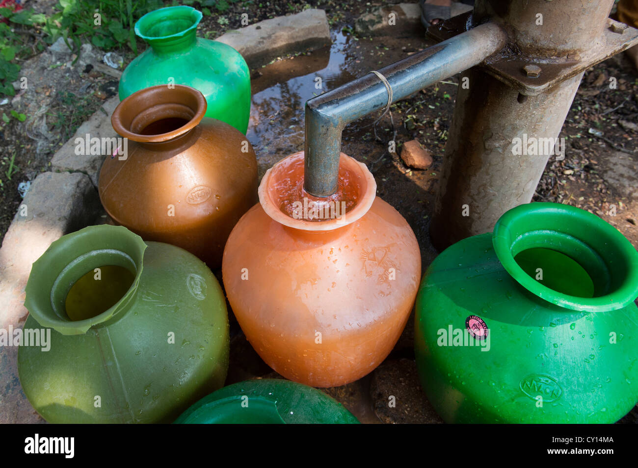 Le remplissage des pots en plastique de l'eau des indiens d'une pompe à eau en milieu rural. L'Andhra Pradesh, Inde Banque D'Images