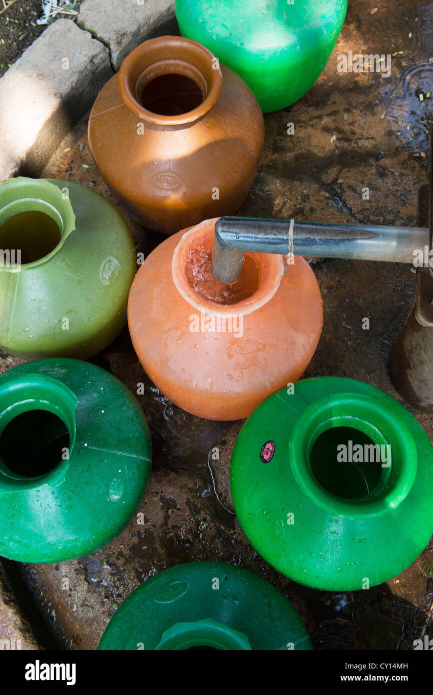 Le remplissage des pots en plastique de l'eau des indiens d'une pompe à eau en milieu rural. L'Andhra Pradesh, Inde Banque D'Images