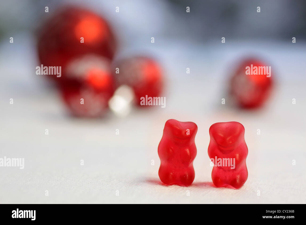 Deux ours gommeux rouge avec des boules rouges sur une nappe blanche Banque D'Images