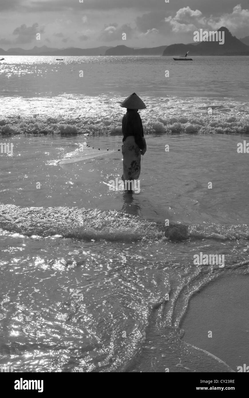 Une femme jette son filet de pêche dans la mer à Selong Belanak sur Lombok, Indonésie Banque D'Images