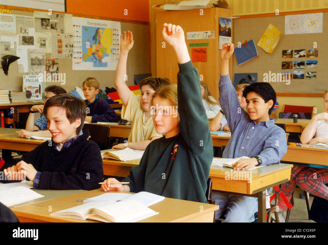 Les enfants de l'école élémentaire assis à un bureau individuel dans la classe suédois mains pour répondre aux questions Banque D'Images