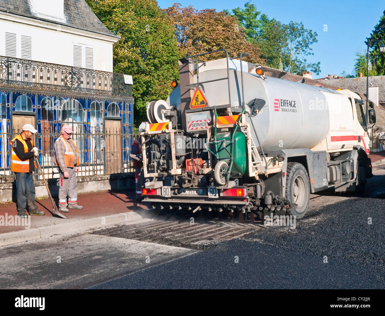 La pulvérisation de pétroliers du bitume chaud sur la surface de la route / renouvellement tarmac - France. Banque D'Images