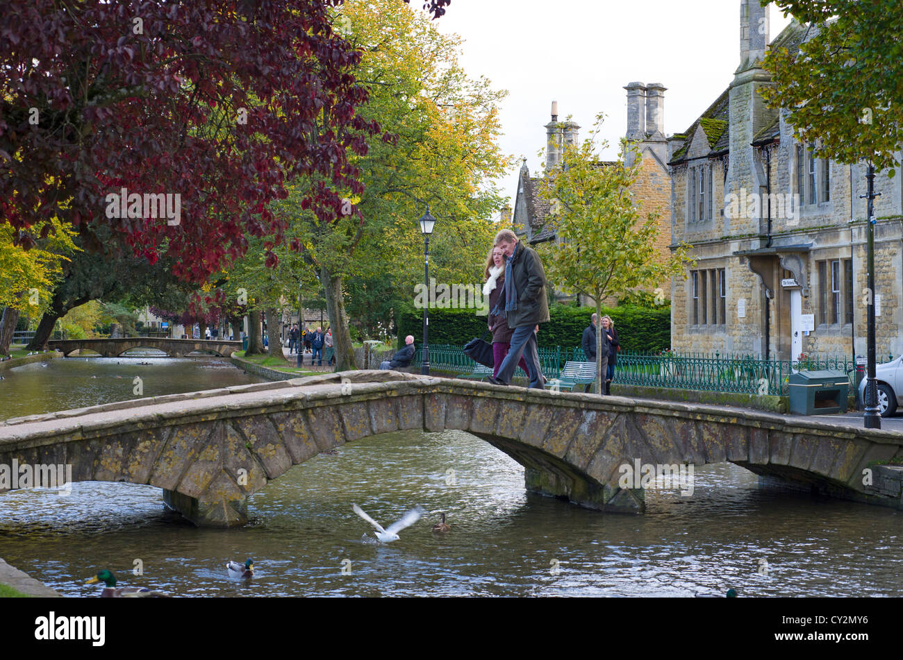 Village de Cotswold Bourton-on-the-water avec touristes traversant le pont sur la rivière Windrush, Gloucestershire, Angleterre Banque D'Images