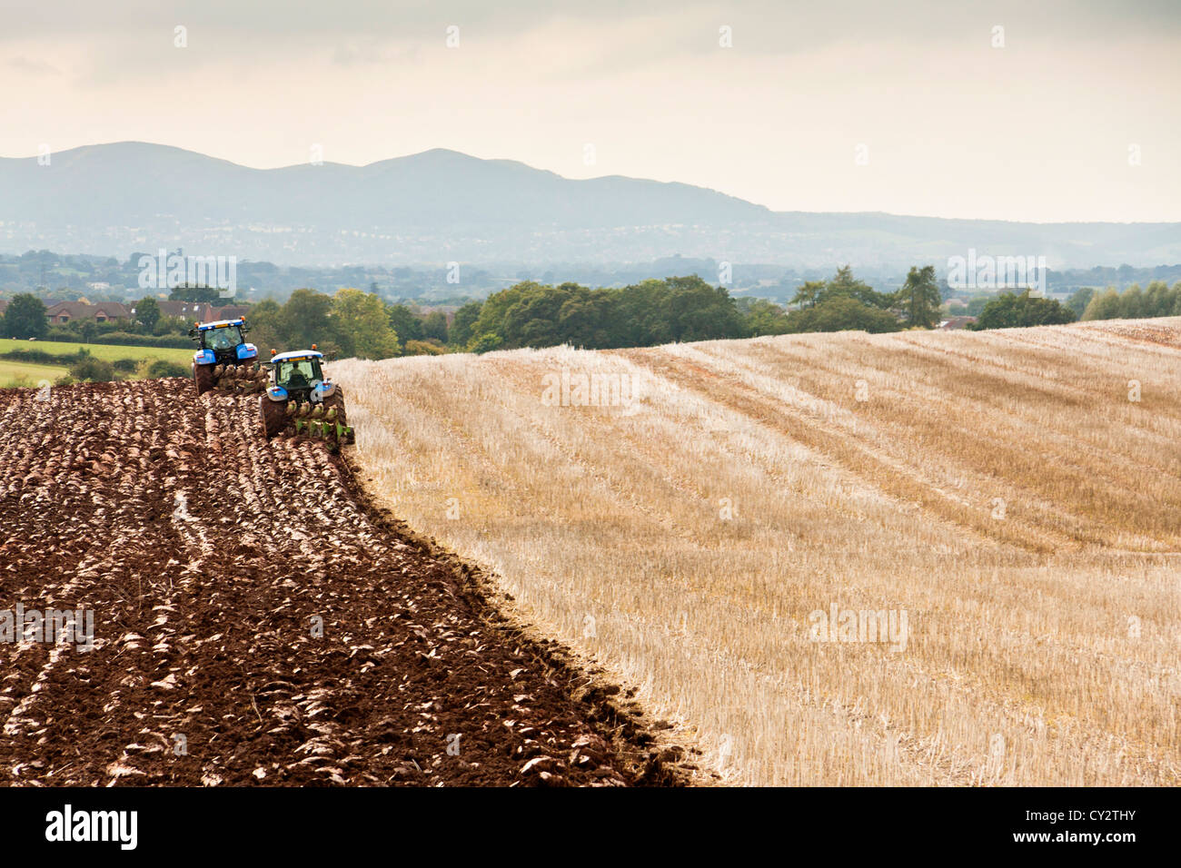 Deux tracteurs labourant un champ près de collines de Malvern Worcestershire).image paysage. Banque D'Images