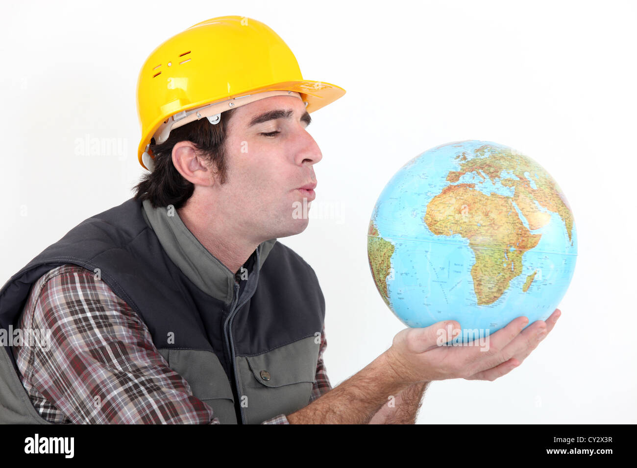 Travailleur de la construction en soufflant sur globe Banque D'Images