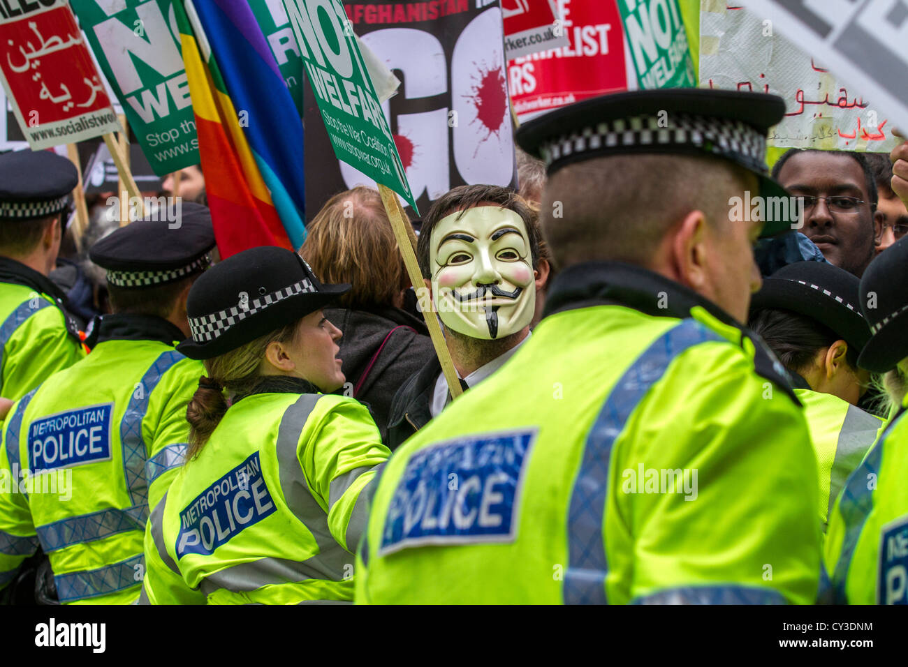 Un manifestant masqué à arrêter la guerre rassemblement à Trafalgar Square, Londres, UK, regarde par la police. Banque D'Images