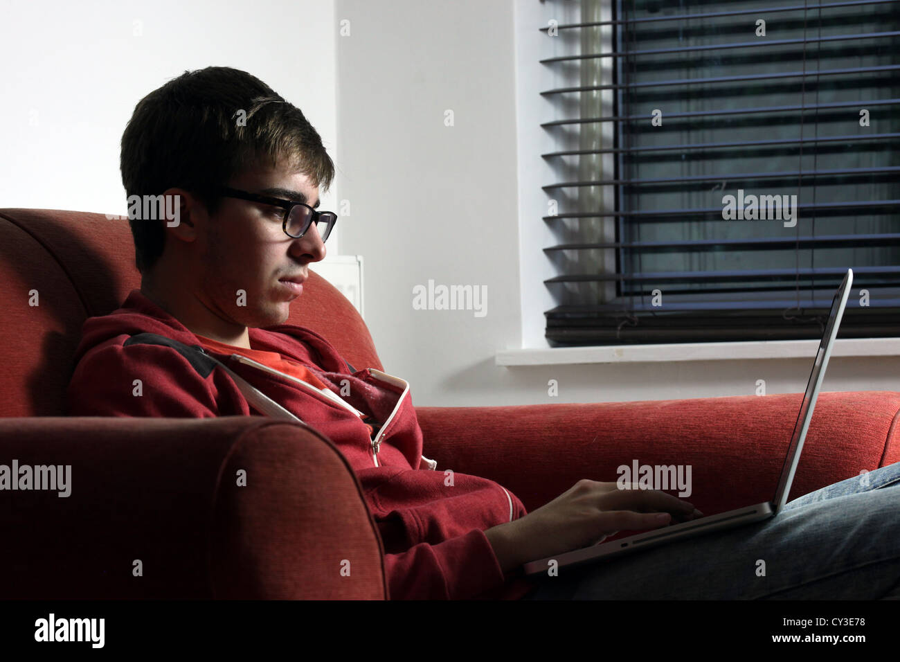 Jeune homme portant des lunettes à l'aide d'un ordinateur portable. Banque D'Images