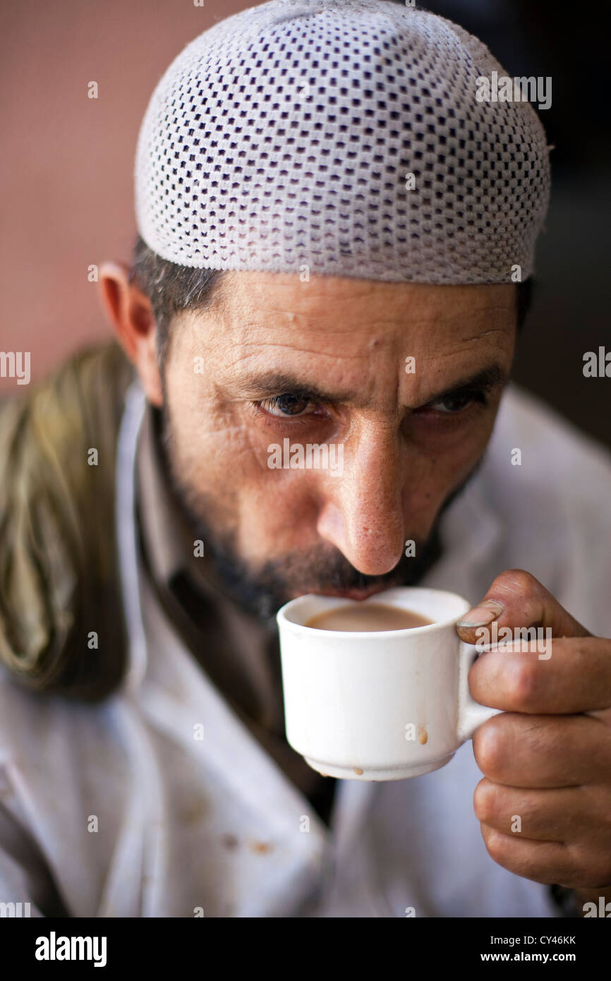 Un waza ou cuisinier traditionnel dans la tradition du Cachemire est en appui et des boissons d''un plateau entre la cuisine et le service des aliments à Wazwan fête. Banque D'Images