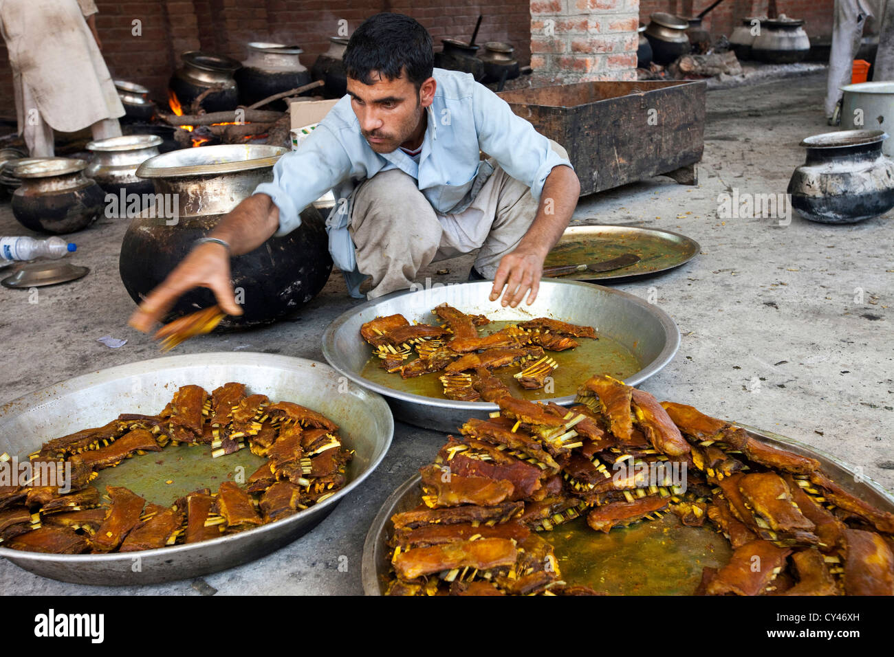 Un waza ou traditionnelle cook Kashmiri sortes de pièces le plat Tabakh Maats - Côtes d'agneaux - lors d'une fête Wazwan. Banque D'Images