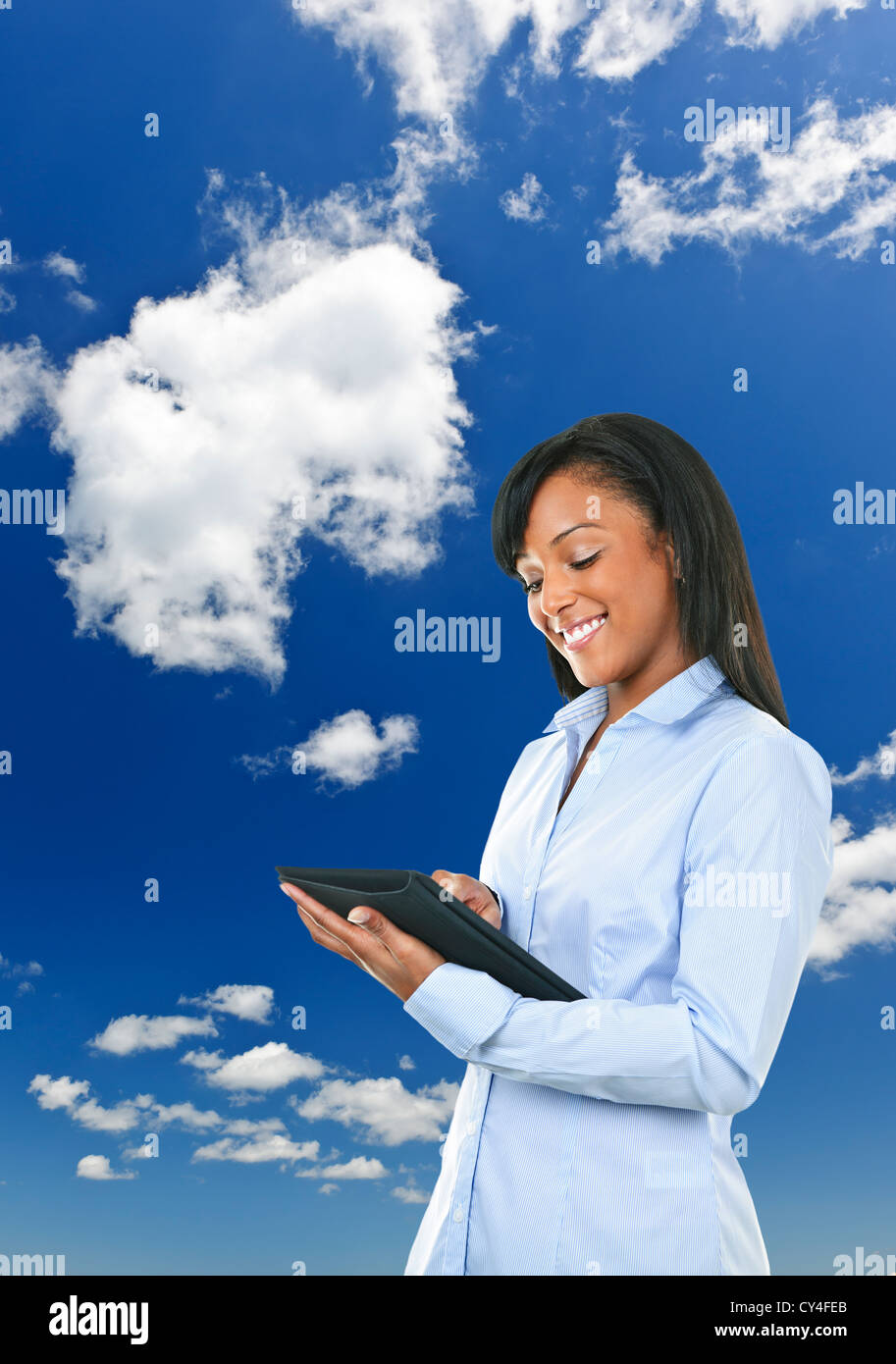 Smiling black woman with tablet computer plus de nuages et ciel bleu Banque D'Images