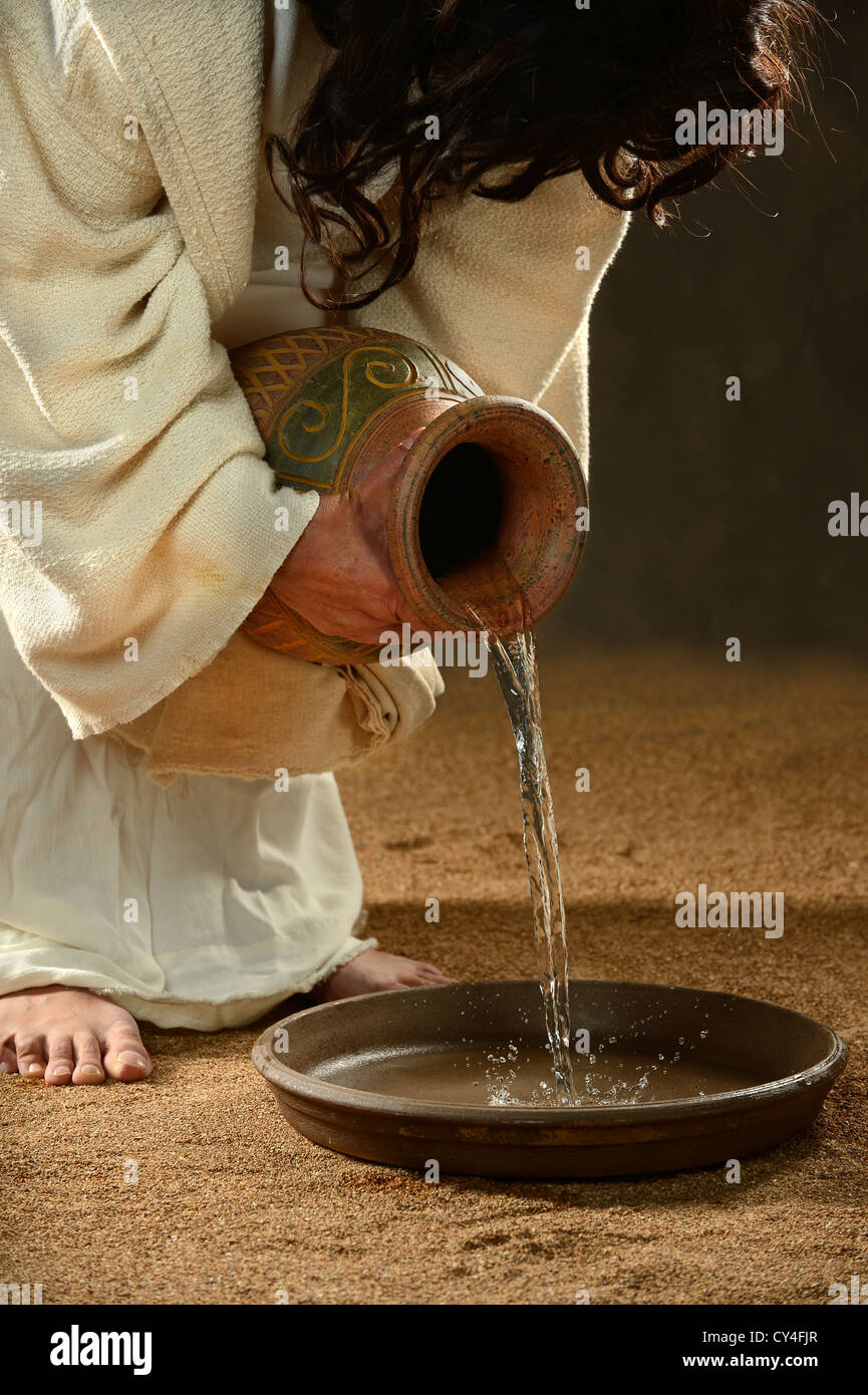 Jésus verser de l'eau dans un récipient sur fond sombre Banque D'Images