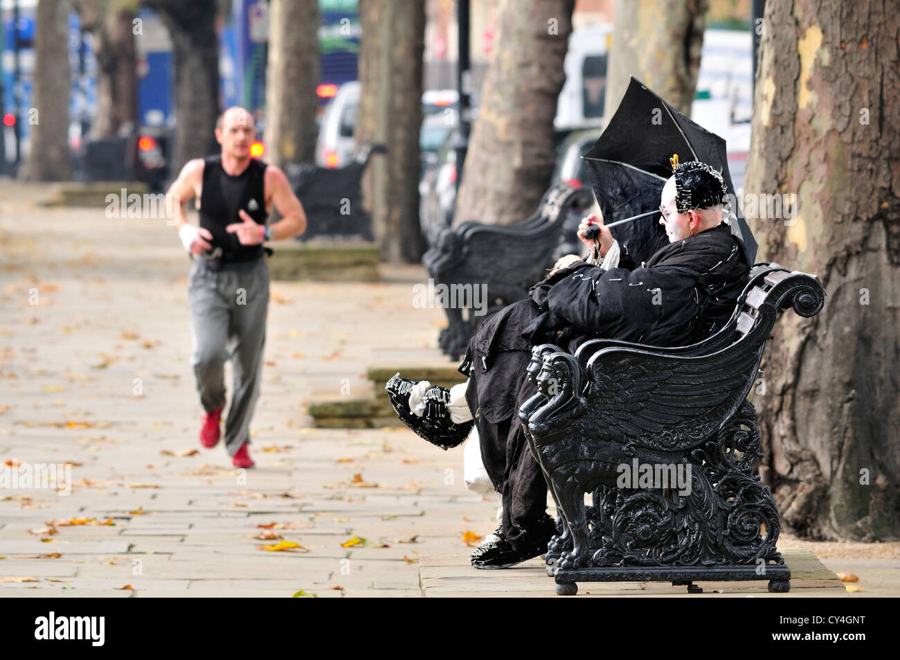 Londres, Angleterre, Royaume-Uni. Homme vêtu de noir avec un visage blanc et couverts dans les épingles de sûreté, avec un parapluie sur une journée ensoleillée Banque D'Images