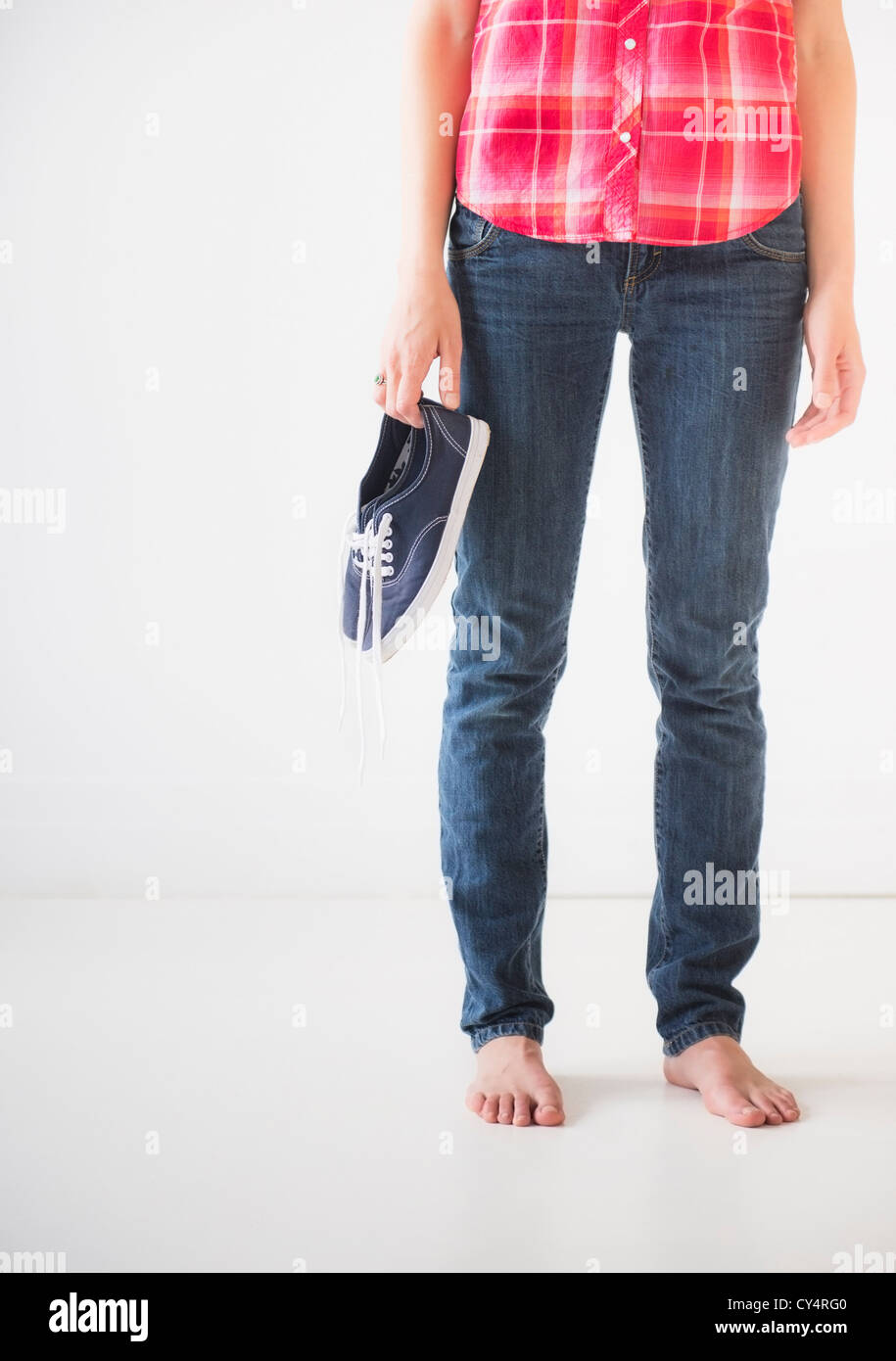 Studio shot of young woman holding barefoot shoes, low section Banque D'Images