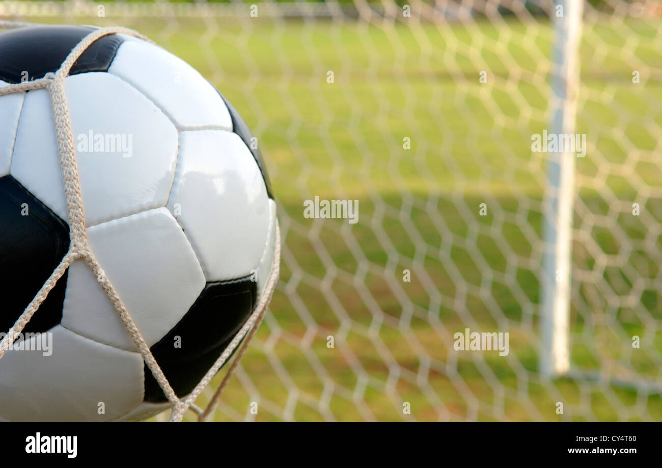 Foot - ballon de soccer dans le cadre de l'objectif contre un champ Banque D'Images