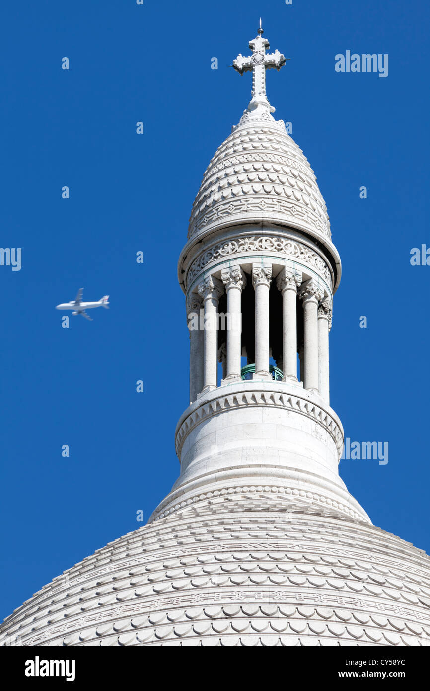Un avion passe le dôme ovoïde de la Basilique du Sacré-Coeur, Montmartre, Paris, France. Construit 1875-1914. Banque D'Images