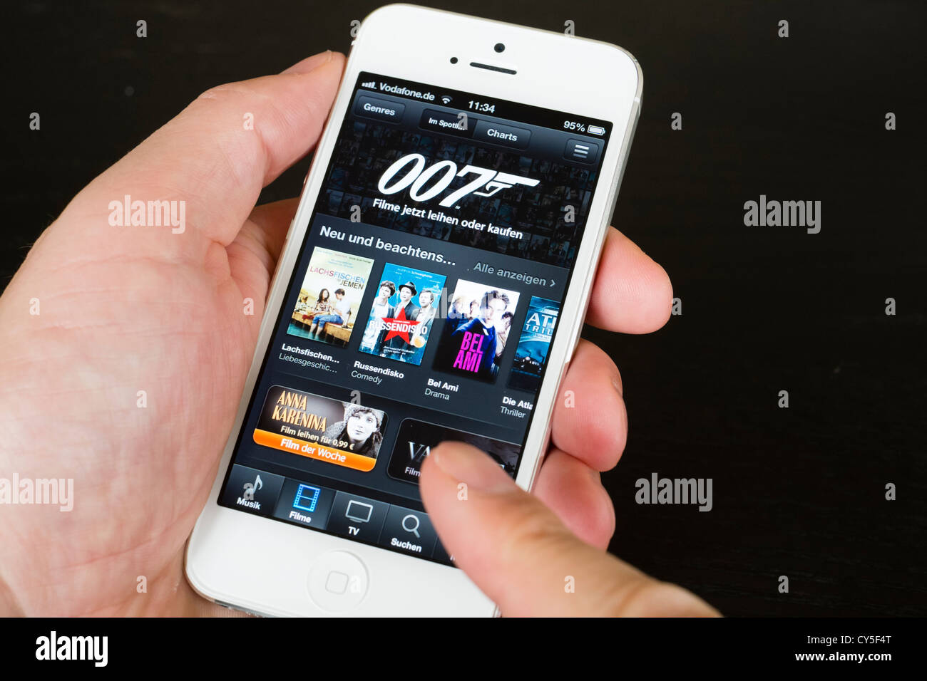 Libre de man holding nouvel iPhone 5 smart phone montrant iTunes Movie Store Banque D'Images