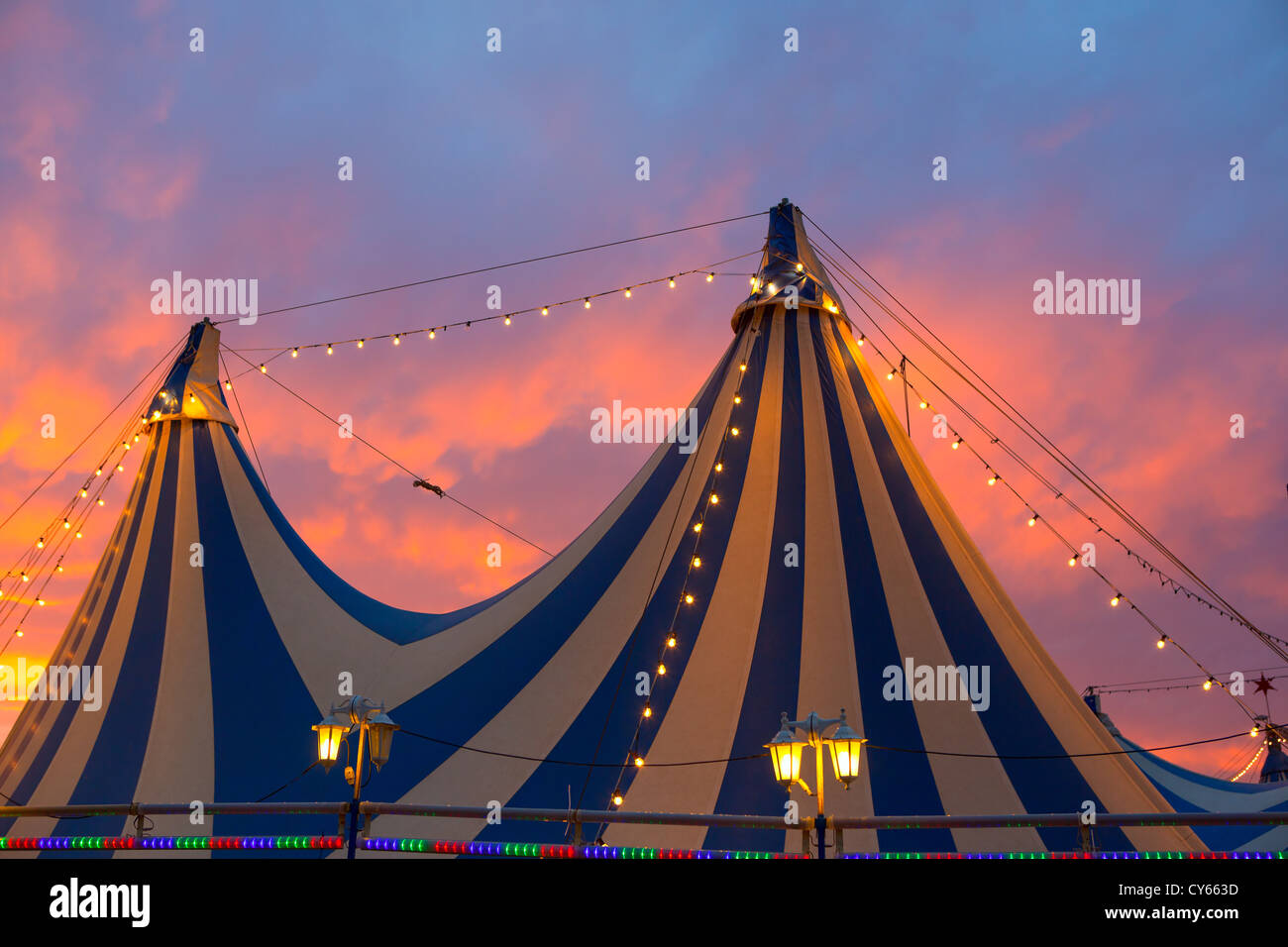 Tente de cirque dans un ciel coucher de soleil spectaculaire orange bleu avec des lumières colorées Banque D'Images