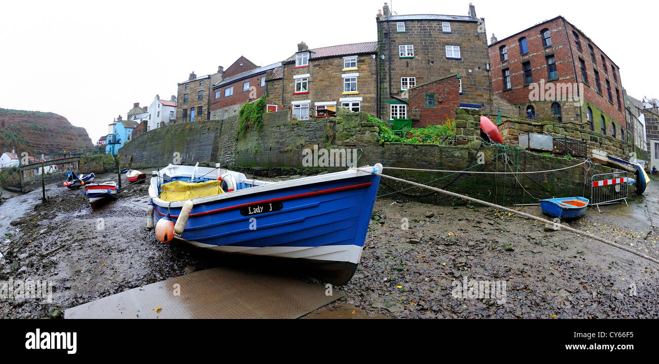 Petits bateaux de pêche amarrés sur un terrain boueux banque cailloux à marée basse avec les bâtiments à plusieurs étages Banque D'Images